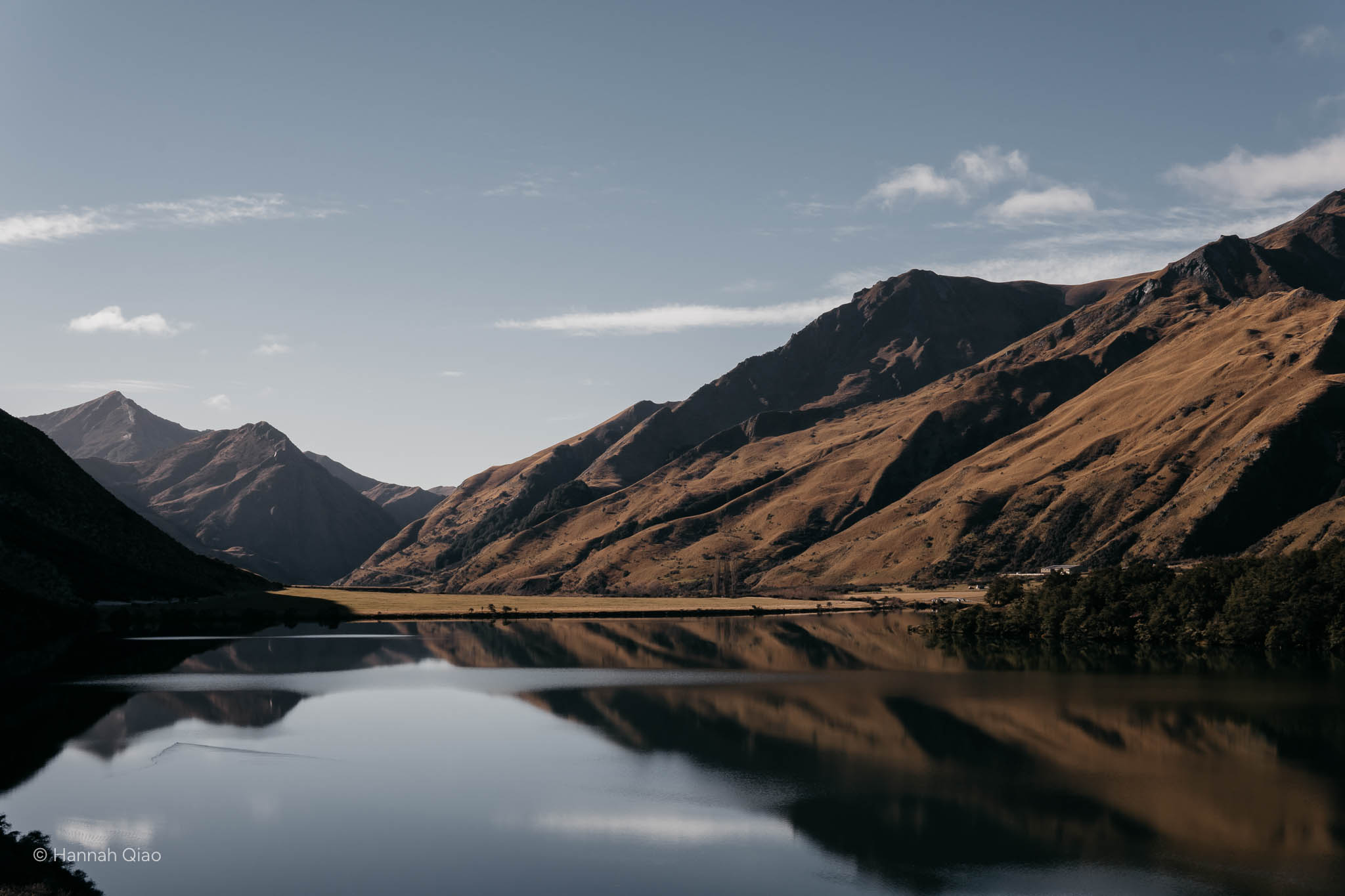 Photo of a lake with grassy hills behind it