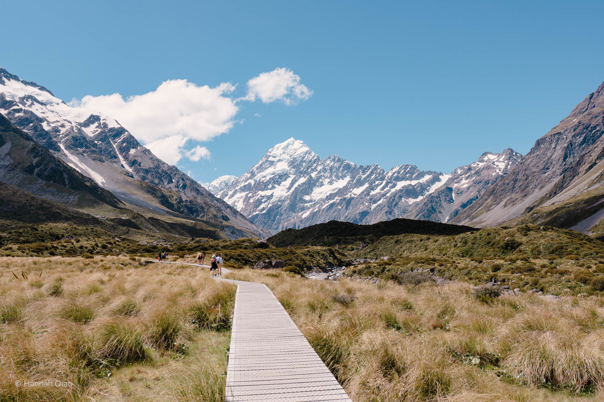 Photo with a path leading towards a snowy mountain on a sunny day