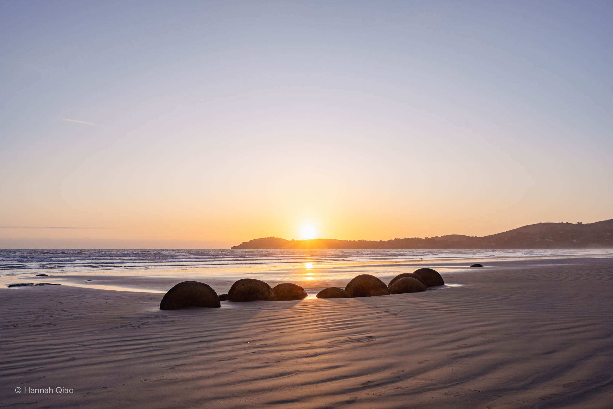 Photo of round boulders at a beach during sunrise